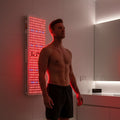 Brightside Longevity Core 1500 full spectrum red light therapy panel mounted on a bathroom wall, used by a man during an at-home wellness session.